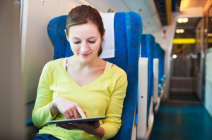 Young woman using her tablet computer while traveling by train